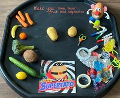 a tray that has some toys and vegetables on it, including carrots, broccoli