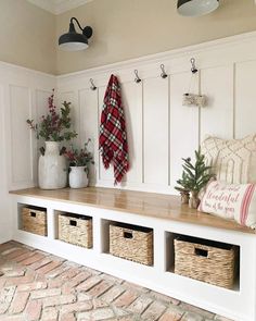 a white bench with baskets on it next to a brick floor