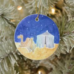 a ceramic ornament hanging from a christmas tree decorated with nativity scene and camels