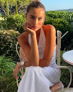 a beautiful woman sitting on top of a white chair