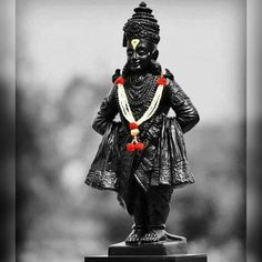 a black and white photo of a statue with beads around it's neck, wearing a headdress