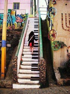 a woman is walking up the stairs to an old piano