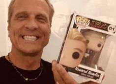 a man holding up a pop vinyl figure in front of his face and smiling at the camera