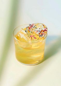 a glass filled with liquid sitting on top of a table next to a white wall