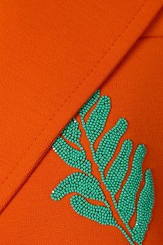 an orange shirt with a green leaf on the front and bottom part of it's sleeve