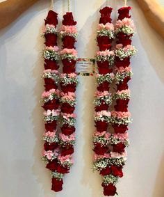 two red and white flowers are hanging on the wall next to a person's hand