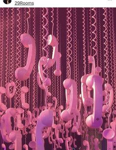 a room filled with lots of pink telephones hanging from the ceiling next to each other