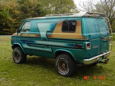 an old green van parked on top of a lush green field