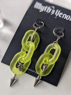 These handmade asymmetrical dangle earrings are made of a semi-opaque lime green acrylic chain, with two and three spikes hanging on each side. They look weighty but are incredibly light, and the matte, yet semi-opaque surface of the chain makes each link luminous and takes on the background tone of its surroundings. These earrings are approximately 2.5" in length on the longer chain side, 2" long on the shorter chain side. ★ GIFT-BOX & WRAPPING AVAILABLE IN CHECKOUT ★ SWAP CLOSURE TYPE: fish hook, lever back, and studs available. Send me a message with your order and I'll be happy to switch it, for free! (Some pieces may not be able to be swapped and depend on stock availability, but I'll try my best to accommodate you!) This set of earrings will come packaged on an M&V earring card in ei Leverback Earrings, Earring Cards, Long Chain, Small Bags, Lime Green, Cyberpunk, Silver Chain, Halloween Shopping, Jewelry Earrings Dangle