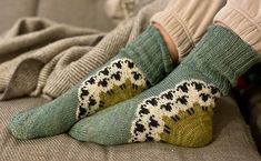 a person sitting on a couch wearing green socks with black and white designs in them