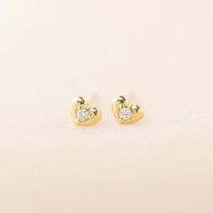 Sweet and petite 14k solid gold heart studs with a single diamond shine in a polish finish. A lightweight yet sturdy piece that is perfect for everyday wear. Simple diamond heart studs to go with any outfit. This earring will make a sweet gift symbolizing feelings of love and appreciation. Purchase this for birthdays, anniversaries or holidays! * Sold as one pair or single stud * Heart width x height: ≈5mm x ≈4mm * Diamond weight: ≈0.03ct (0.015ct for single stud) * Earring post: 10mm long * Clo Tiny Diamond Earrings, Heart Diamond Earrings, Diamond Heart Earrings, Small Earrings Gold, Heart Engagement, Piercing Inspo, Gold Heart Studs, Ruby Earrings Studs, Gold Diamond Earrings Studs