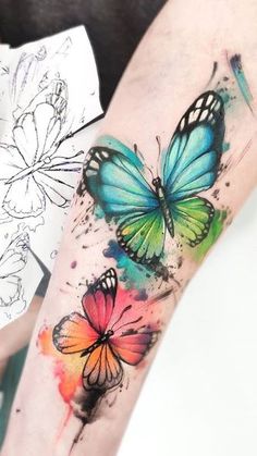 colorful butterfly tattoo on the left forearm and right arm, with watercolor splashs