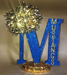 a blue and gold glittered letter m with a tree in the middle that says museum