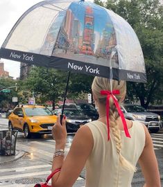 a woman is holding an umbrella in the rain with new york and new york on it