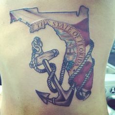 a woman's stomach with an anchor, rope and flag tattoo on the side