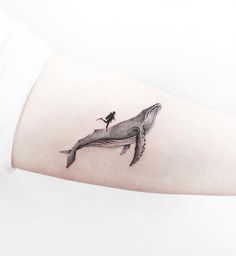 a woman's arm with a small whale tattoo on it