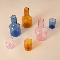 several different colored glass vases sitting next to each other on a white table top