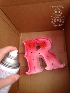 someone is holding a spray bottle in front of the letter r and it's inside a cardboard box