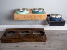 two metal bowls sitting on top of a wooden stand next to each other with their names