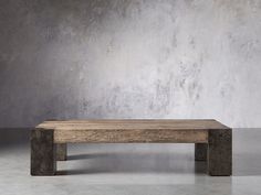 a wooden bench sitting in front of a cement wall with concrete blocks on the floor