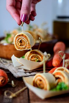 a person is holding a vegetable roll up to take it out of the oven and another food item in the background