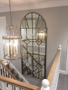 a chandelier hanging from the side of a stair case next to a mirror