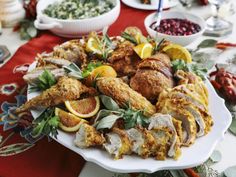 a platter filled with chicken, oranges and cranberries on a table