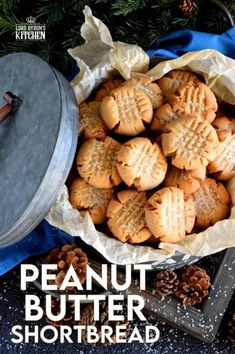 some cookies are in a bowl with pine cones on the table next to it and a cookie tin