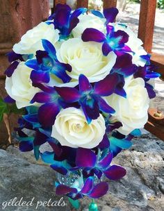 a bouquet of white and blue flowers in a vase on a stone floor next to a fence