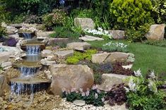 a garden filled with lots of rocks and water flowing down it's side walk