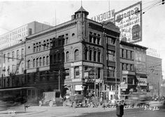 an old black and white photo of a large building on the corner of a street