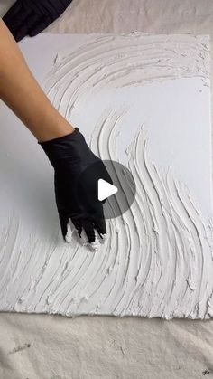 a person in black gloves is painting a white wall with white paint on the floor