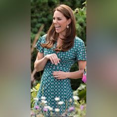 the pregnant woman smiles as she stands in front of flowers