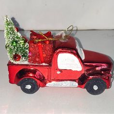 a red truck with a christmas tree on the back is sitting in front of a white wall