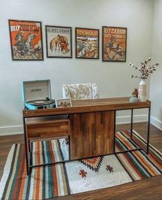 an office with posters on the wall and a rug in front of it, along with a computer desk