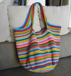 a multicolored crocheted bag hanging on the back of a couch