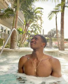 a man sitting in a hot tub with palm trees around him and smiling at the camera