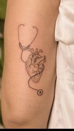 a heart with a stethoscope tattoo on the right side of the arm