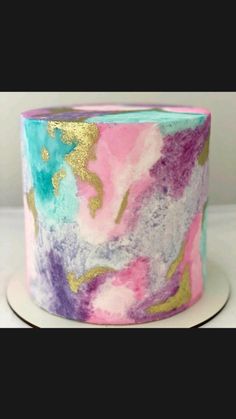 a cake decorated with pink, blue and gold icing on top of a white plate