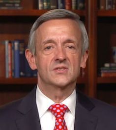 a man wearing a suit and tie in front of bookshelves