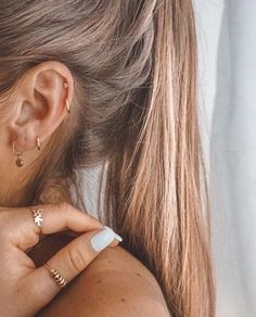 a close up of a person wearing gold rings and ear piercings on their ears