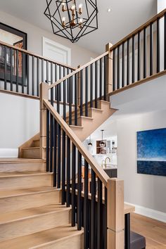 an open staircase leading up to a kitchen and living room with white walls, wood floors and black handrails