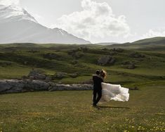 a bride and groom are walking in the mountains