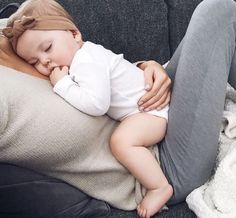 a woman laying on top of a couch holding a baby