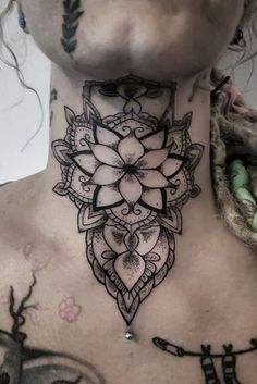 a woman's neck with a tattoo on her chest and an intricate flower design