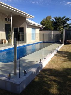 a glass fence around a swimming pool in a backyard