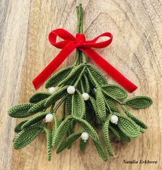 a small christmas tree made out of crochet with red ribbon and white balls