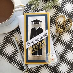 a graduation card on top of a desk next to a cup of coffee and scissors