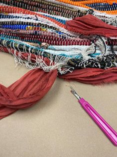 a pink pen sitting on top of a pile of scarves