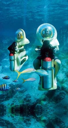 two people in scuba suits are riding on the back of a small motorbike